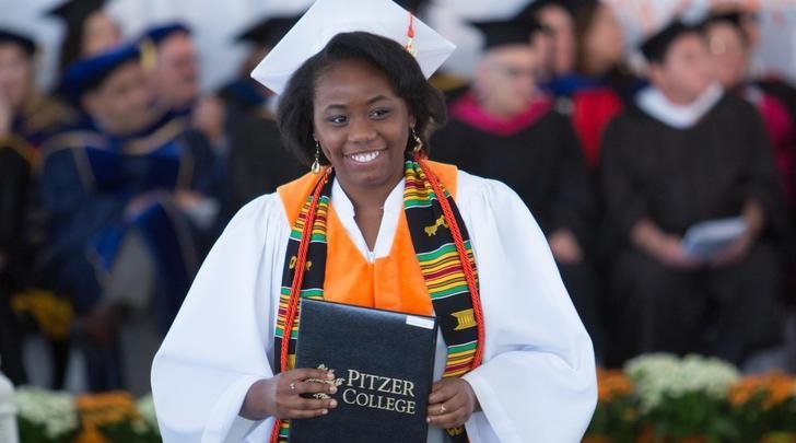 a graduate walks down the aisle with her diploma