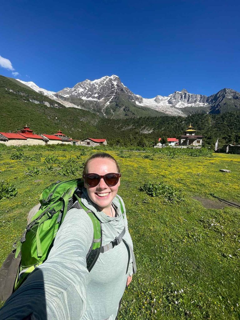 Madison Wilson takes a selfie in Nepal with mountains and temples behind her.