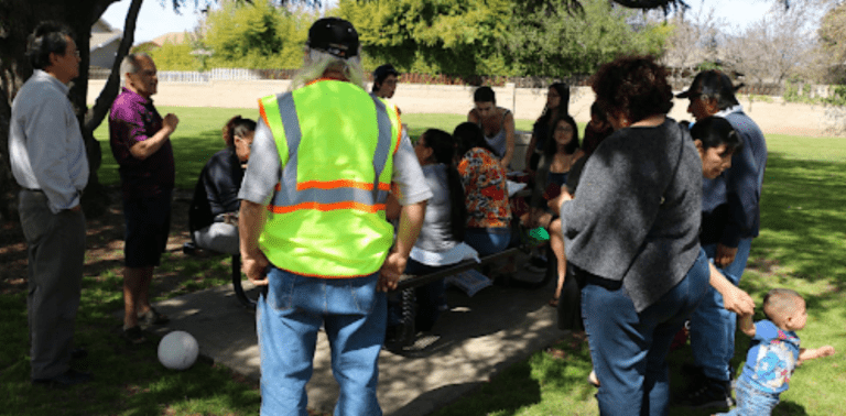 Day laborers outside under a tree with Pitzer students and faculty