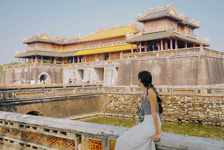 a student sits outside a historical building in the city of hue, vietnam