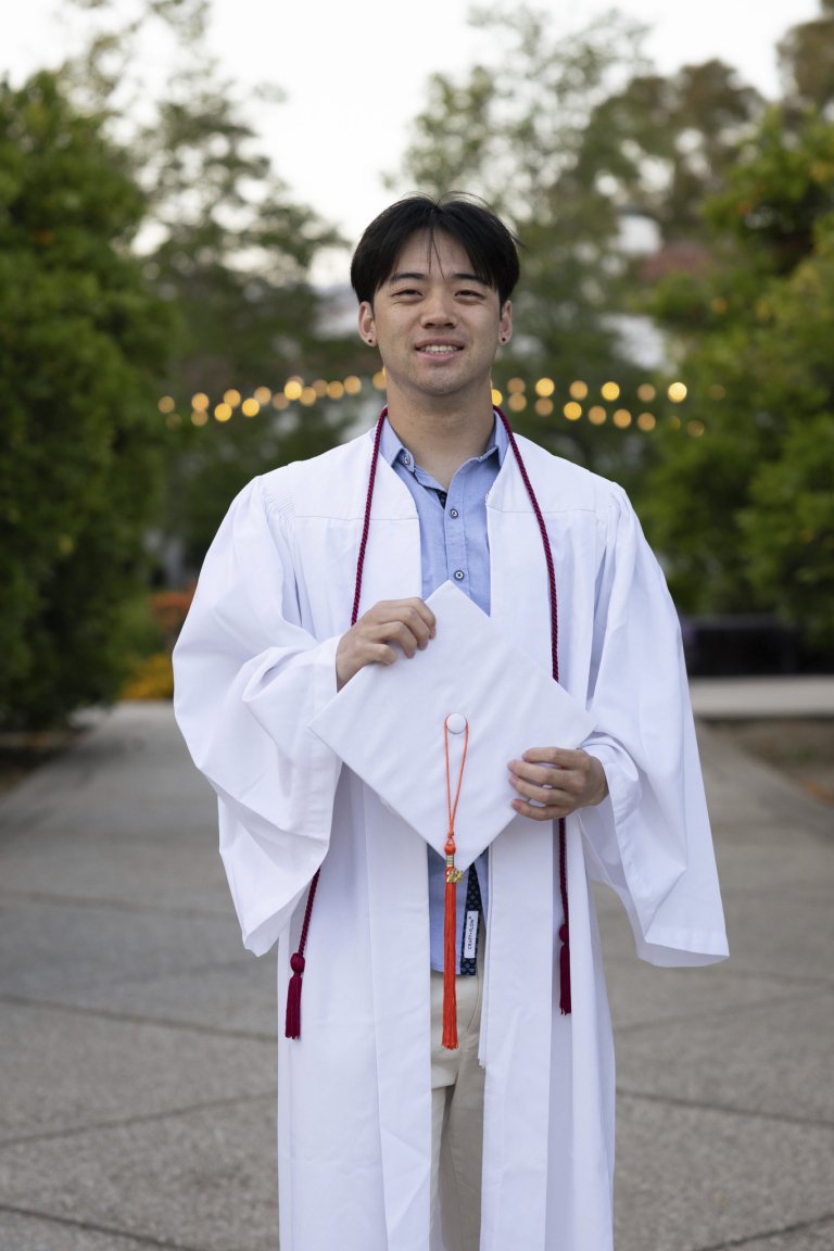 Aidan Tu posing in his graduation cap and gown