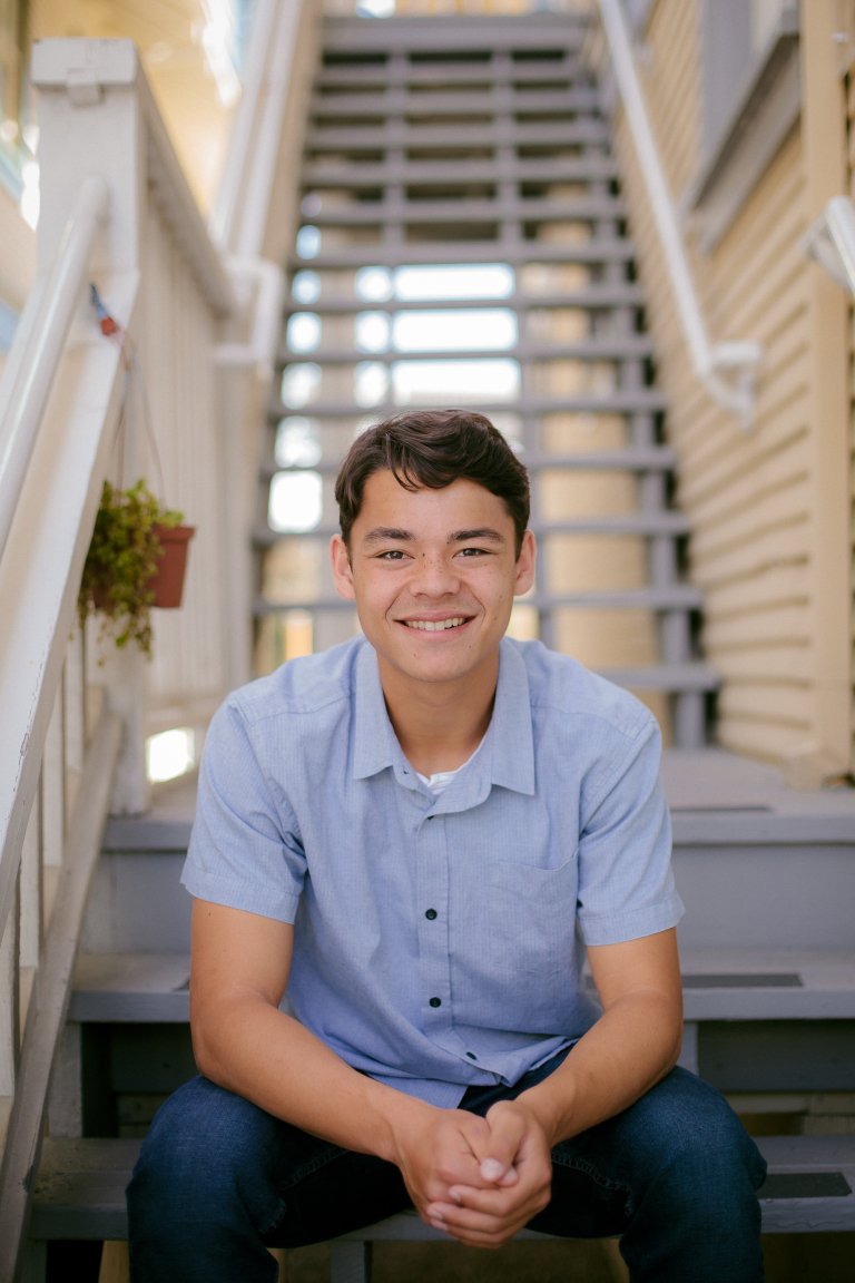 Ethan sits at the bottom of a staircase and smiles
