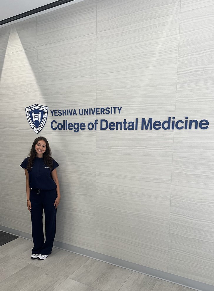 Sarrah Zanzi stands in front of a wall with the College of Dental Medicine sign