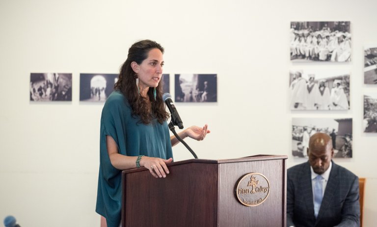 Tessa speaks in front of a podium in the Founder’s room at Pitzer College