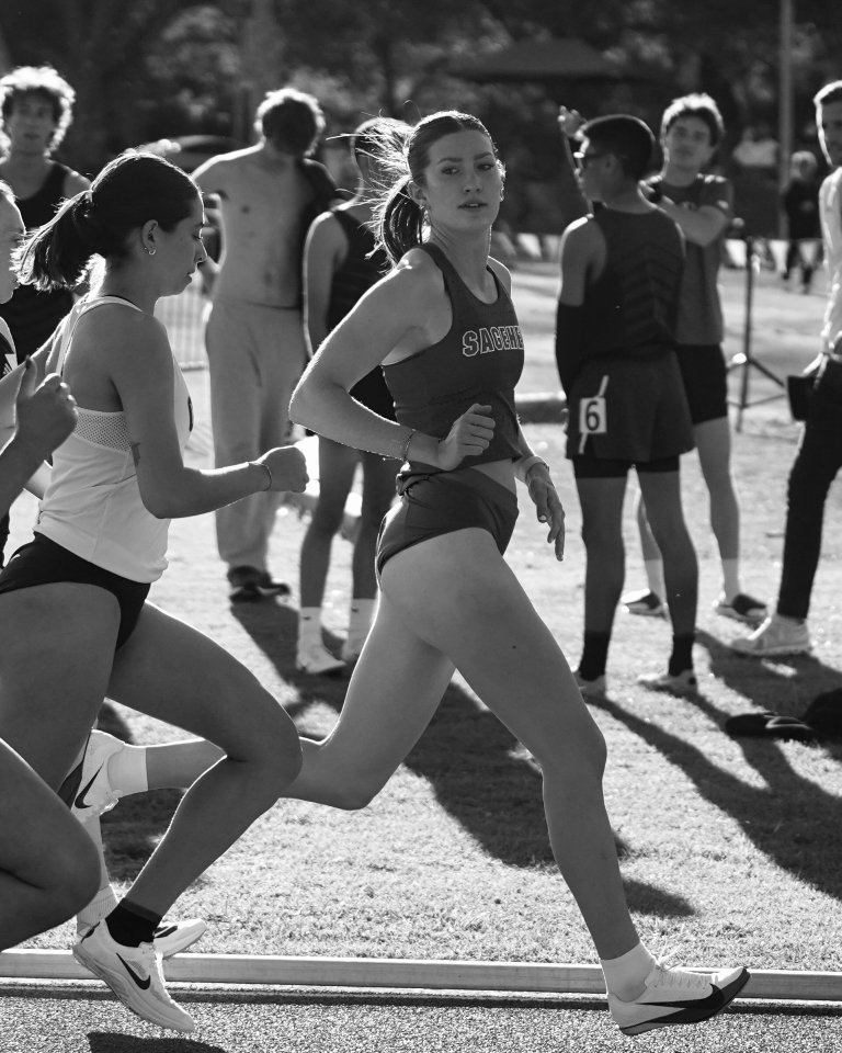 Eva runs in a race and looks to the right at the camera. 