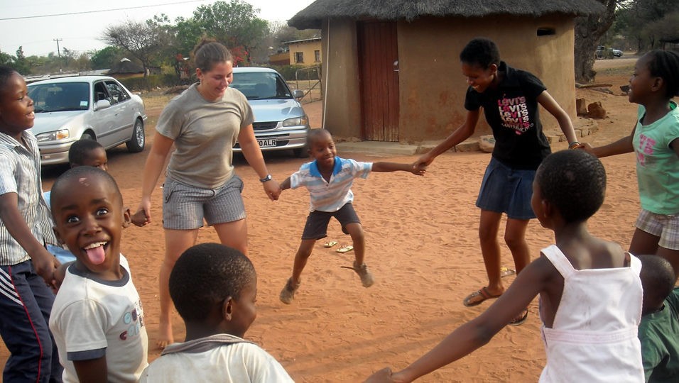 Children in Botswana and Pitzer student hold hands in a circle.