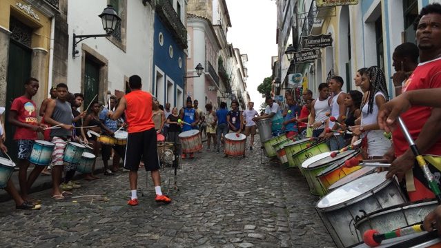 Drummers line a cobblestone street in Brazil.